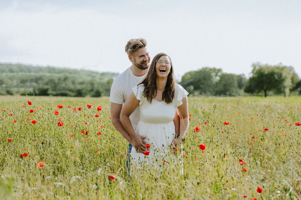 Fotograf Reutlingen Tübingen Hochzeit Paar steht in einem Mohnblumenfeld und lacht herzlich in Tübingen