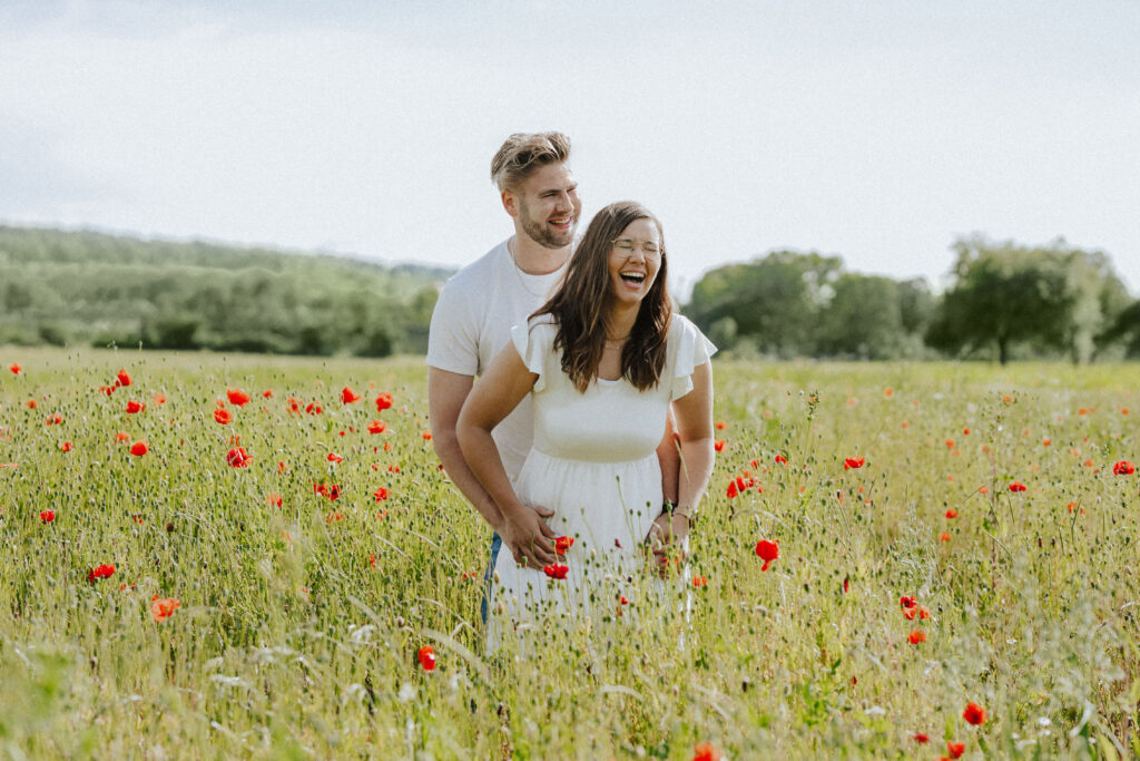 Fotograf Reutlingen Tübingen Hochzeit Paar steht in einem Mohnblumenfeld und lacht herzlich in Tübingen