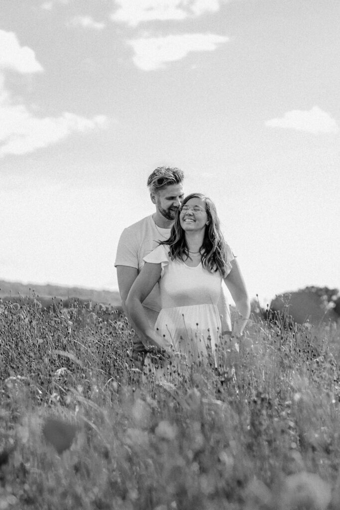 Fotograf Reutlingen Tübingen Hochzeit Paar steht in einem Mohnblumenfeld und er flüstert ihr etwas ins Ohr in Tübingen