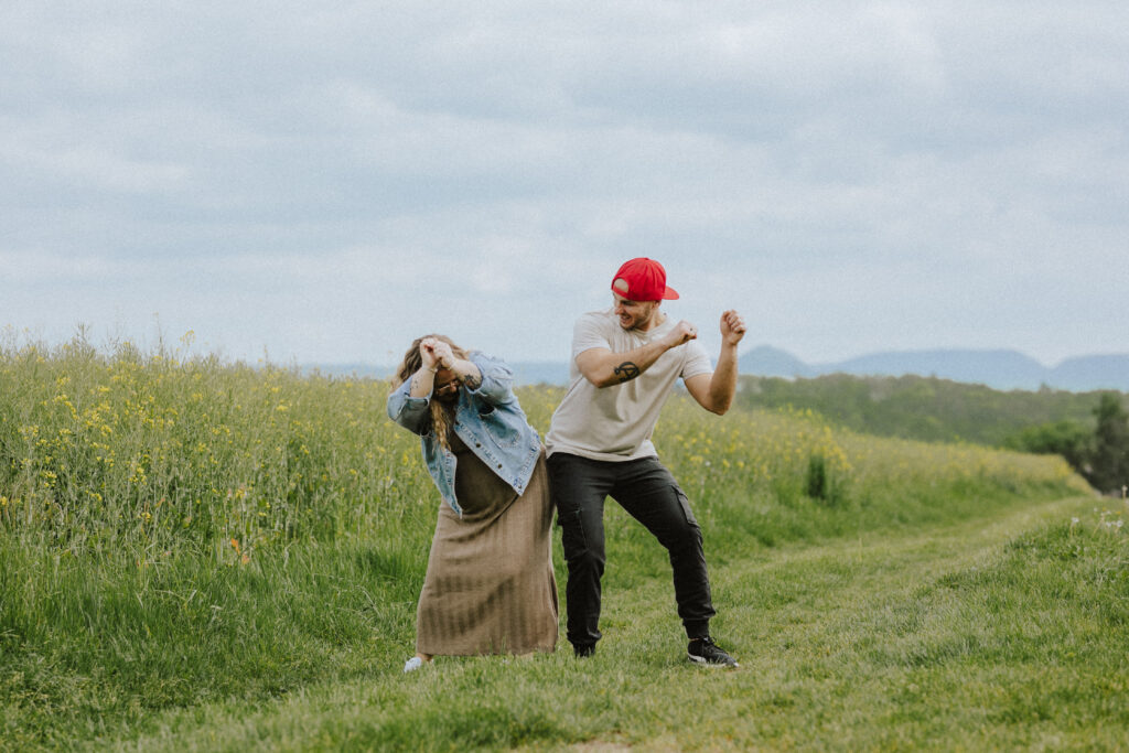 Fotograf Reutlingen Tübingen Hochzeit Paar läuft an einem Rapsfeld entlang und macht einen Hip Bump in Pliezhausen