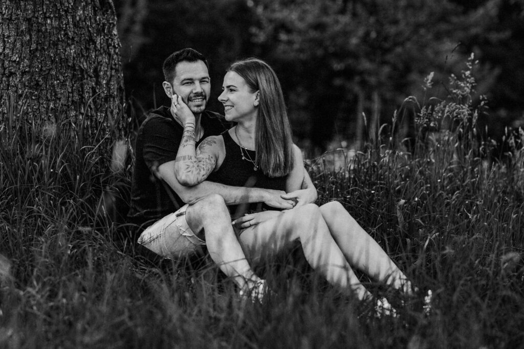 Fotograf Reutlingen Tübingen Hochzeit Paar sitzt vor einander in einer Wiese und sie streichelt ihn an der Wange in Walddorfhäslach